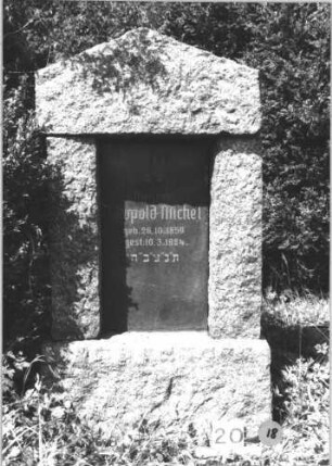 Grabstein 18 (Index: 99805258) Material: Granit, schwarze Marmorplatte Zustand: gut, Schriftplatte quer gesprungen Maße HxBxT: 149x77x24 cm Beschreibung: ädikulaartige Stele mit Pfeilern, Sockel, giebelartiger Abschluß, rechteckige Schriftplatte: Grabstein 18