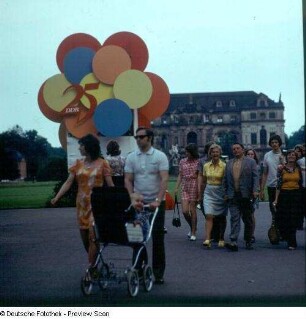 Spaziergänger vor Werbeaufsteller "25 Jahre DDR" am Palais im Großen Garten