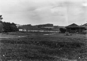 Landschaft in Brasilien : Eine hügelige Graslandschaft in Brasilien. Rechts ein Stall, links Gebäude hinter einer Baumgruppe. Im Hintergrund teilweise bewaldete Hügel.