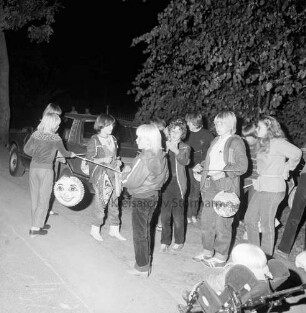Laternenumzug: Freiwillige Feuerwehr Mönkhagen: vorn Kinder mit Laternen: dahinter Jugendliche: vorn rechts Kind in Kinderkarre: hinten links Pkw: hinten rechts Bäume: Nacht