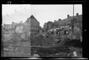 Nicht identifizierbare Ortschaft im Artois (historische Provinz im Dep. Pas-de-Calais, Frankreich) oder in Flandern (Belgien): Schutthaufen eines zerstörten Gebäudes neben und vor teilweise zerstörten und unzerstörten Häusern