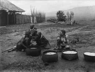 Gruppe in Tukuyu : Eine Gruppe von indigenen Dorfbewohnern in dem Dorf Tukuyu neben Körben mit Anbauprodukten. Unter ihnen eine Frau mit Albinismus.