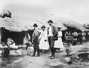 Expeditionsleiter Bruno Knochenhauer mit seinem Schwager Richard Zimmermann (Mitte) bei einem Aufenthalt in einem koreanischen Dorf. Am Boden Transportkisten für die Ponykarawane