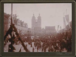 Menschenmenge auf festlich geschmücktem Marktplatz.