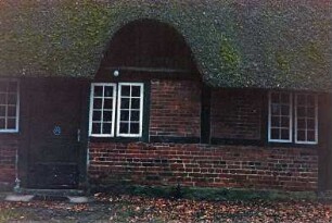 Nütschau: Schloßstraße 42a-c: traufständige Mehrfamilienkate aus Fachwerk mit Reetdach: Straßenfront, Teilansicht Mitte: Eingangstür, Sprossenfenster, Heuluke