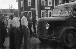 Omnibus : Einige Männer stehen vor einem Bus.