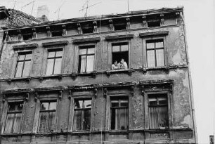 Wohnhaus. Teilansicht der Fassade mit zwei Frauen an einem Fenster