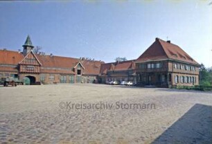 ehemaliges Gut Trenthorst-Wulmenau: Trenthorst: Wirtschaftshof [Karree]: Blick von Südwesten: rechts östlicher Kopfbau mit Arkaden, links Torhaus mit Uhrturm und Durchfahrt