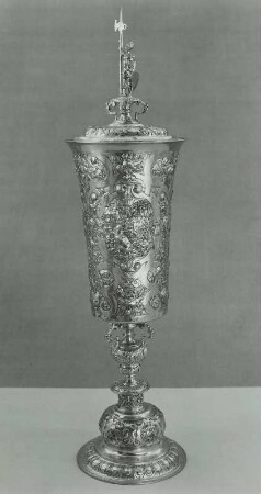 Hoher Pokal mit Deckel mit drei hochovalen Feldern mit je einem Tier in Landschaft zwischen Ornament, auf dem Deckel ein Ritter mit Schild und Hellebarde