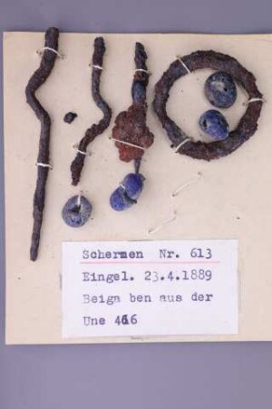 Schmuckbeigaben: Blaue Glasperlen, Stabkopfnadeln und Eisenring