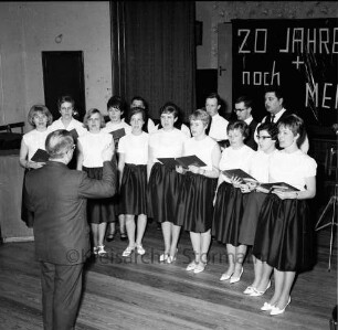 Landjugend Bargteheide: Feier zum 20-jährigen Jubiläum: Schützenhof: Festsaal: Generalprobe: Chor der Bargteheider Landjugend singt: Chorleiter Wilhelm Schienkiwitz: im Hintergrund Bühne, Transparent "20 Jahre + noch mehr?", 10. März 1967