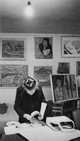 Die Malerin Charlotte E. Pauly in einem Ausstellungsraum (Galerie Berlin ?) beim Blättern in einem Skizzenbuch