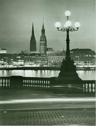 Hamburg-Altstadt bei Nacht. Blick von der Lombardsbrücke über die Binnenalster Richtung Hamburger Rathaus. Im Hintergrund der Turm des Mahnmals St. Nikolai