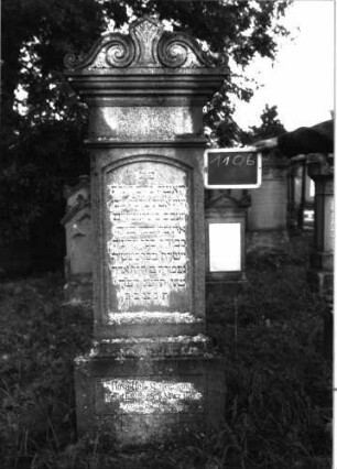Grabstein 1106 (Index: 100104175) Material: Muschelkalk Zustand: gut erhalten Maße HxBxT: 193x51x20 cm Beschreibung: aufgesockelte Stele mit unten mehrfach profiliertem Giebelaufsatz, Aufsatz mit Voluten und stilisiertem Akanthus, Schriftfeld eingetieft, mit Segmentbogenabschluss, deutsche Inschrift durch rechteckige Rahmenlinie gerahmt Symbolik: Voluten, Akanthus: Grabstein 1106