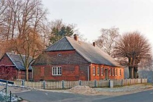 Höltenklinken: Klinken 5: traufständiges Bauernhaus: Giebelseite Wohntrakt: Straßenfront mit vorgesetzter Backsteinfassade, Eingangstür: davor Bäume, Vorgarten, Lattenzaun: vorne nach links Hauszufahrt: hinten links Nebengebäude aus Fachwerk: