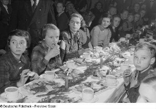 Kinder an einer gedeckten und geschmückten Tafel bei der Weihnachtsfeier des Verlags Volk und Wissen