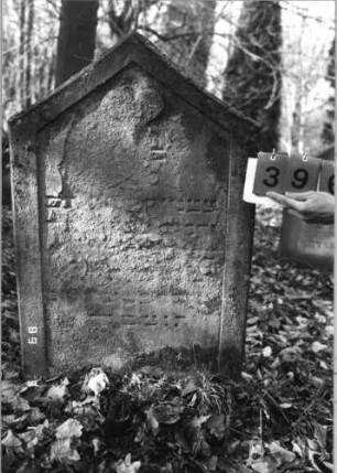 Grabstein 396 (Index: 99752644) Material: Sandstein Zustand: stark abgeblätt. m. fast völl. Textverlust Maße HxBxT: 100x60x10 cm Beschreibung: Stele, giebelartiger Abschluß, Schriftfeld eingetieft Symbolik: Herz: Grabstein 396