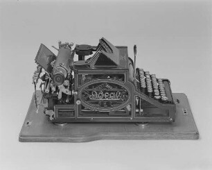 Typenhebelschreibmaschine "Ideal" (Modell A 3). Erste deutsche Typenhebelschreibmaschine mit Vorderanschlag (sofort sichtbare Schrift), 42 Tasten, Farbband. Seitenansicht von links oben