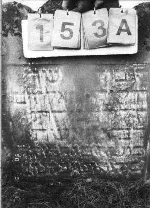 Grabstein 153 (Index: 100114709) Material: Sandstein Zustand: sehr stark verwittert mit großem Textverlust, unterer Teil eingesunken, untere Zeilen eingesunken Maße HxBxT: 64x56x10 cm Beschreibung: Stele mit dreigeteiltem Rundbogen: Grabstein 153A