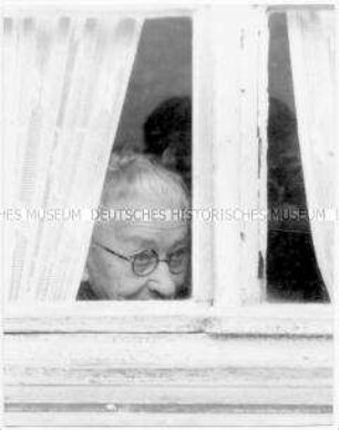 Alte Frau schaut aus dem Fenster