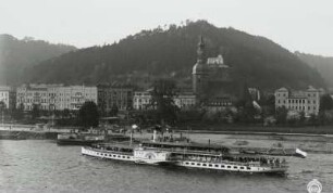 Personen-Seitenraddampfer "Leipzig" (1929; Werft Dresden-Laubegast) auf Fahrt stromab bei Ansteuerung der Landungsbrücke : Bad Schandau. Personen-Seitenraddampfer "Leipzig" (1929; Werft Dresden-Laubegast) auf Fahrt stromab bei Ansteuerung der Landungsbrücke. Blick vom linken Uferhang über die Elbe auf Hotelbauten und Stadtkirche