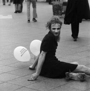 Ein Artist / Clown mit Rollschuhen sitzt auf dem Bürgersteig