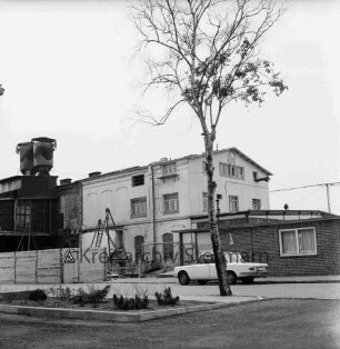 Kampnagel AG: Kampstraße: Eisengießerei: links davor Bretterzaun, rechts Pkw: vorn Blumenrabatte und Baum