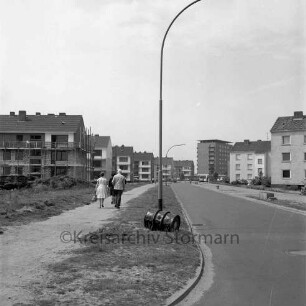 Stonsdorfer Weg: links Baustelle eines Wohngebäudes, dahinter und rechts weitere Wohngebäude, im Hintergrund das Rathausgebäude: Blick von Osten