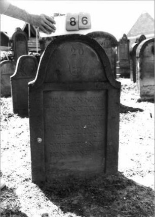 Grabstein 86 (Index: 99798159) Material: Sandstein, rot Zustand: leicht verwittert Maße HxBxT: 95x63x11 cm Beschreibung: Stele, geschweifter Abschluß: Grabstein 86