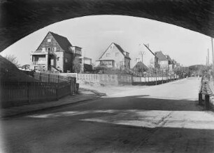 Coswig, Straßenansicht Hohensteinstraße. Blick durch die Eisenbahnbrücke nahe Bahnhof Neucoswig gegen Wohnhäuser mit Einfriedung