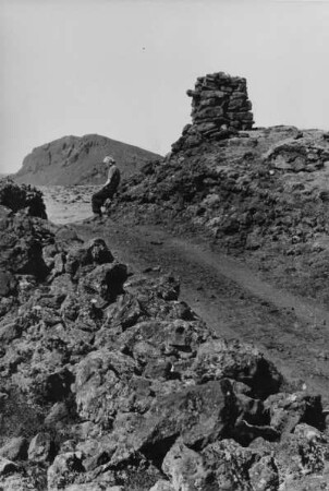 Lotte Ehrhardt in Lavawüste mit 'Steinmann' (Wegweiser) oben rechts, Island