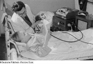 Ein Mann hält einem lesenden Kind ein Mikrofon im Dr.-Georg-Sacke-Heim
