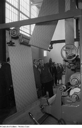 Besucher der Leipziger Herbstmesse 1954 betrachten eine Textilmaschine