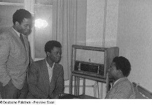 Drei Studenten, vor einem Radio sitzend