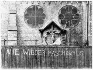 Außenansicht einer Kirche mit Kruzifix und dem Graffiti "Nie wieder Faschismus" (Altersgruppe 14-17)