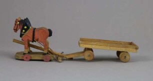 Zwei hölzerne Pferde mit einem Leiterwagen auf Rädern
