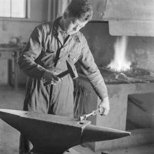 Lehrling von Borgward beim Schmieden am Amboss mit Hammer und Zange