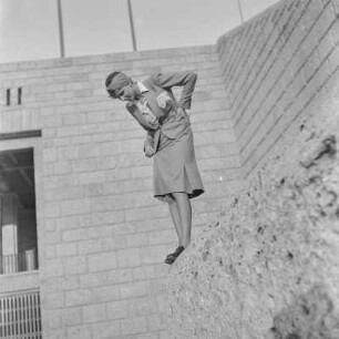 Frau im Kostüm steht auf einer Mauer