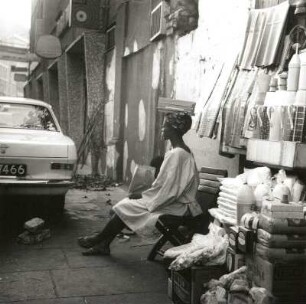 Lagos, Nigeria. Straßenbild mit Nigerianerin an einem Verkaufsstand