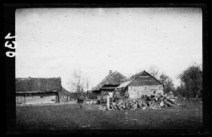 bei Wirballen (?) (=Virbalis, Litauen): Blockhäuser mit Reetdach, davor eine Holzlege mit Baumstämmen ("Dorf")