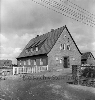 Amt Mollhagen: Amtshaus: vorn rechts Mauer mit Zaun: links Holzzaun: dahinter Baustelle und hinten Wohnhaus: hinten rechts kleines Haus