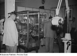 Fachbesucher vor einer Vitrine mit Kameraobjektiven