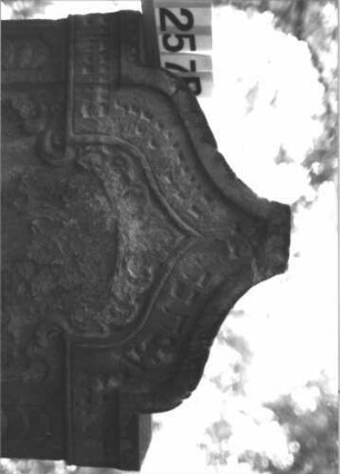 Grabstein 1257 (Index: 99900073) Material: Sandstein Zustand: stark verwittert Maße HxBxT: 125x69x13 cm Beschreibung: Stele mit Kielbogenabschluss, im Bogenfeld Akanthusornamente, seitlicher Rahmen mit Schuppenfries Symbolik: Akanthus, Schuppenfries: Grabstein 1257B