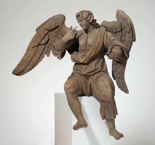 Zu einem Engelspaar gehörig: sitzender Engel, nach links gewendet, mit ausgebreiteten Flügeln, mit der Rechten auf sein Gesicht weisend