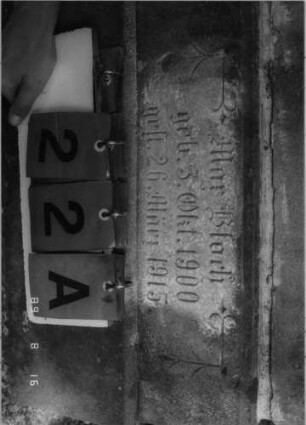 Grabstein 22 (Index: 100086642) Material: Sandstein mit schwarzer Platte Zustand: Sockel leicht verwittert Maße HxBxT: 138x51x23 cm Beschreibung: Stele, getreppter Sockel, Giebel mit Eckakroteren, Schrifttafel rechteckig: Grabstein 22A