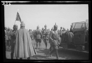 Bei Focșani (Rumänien): Offiziere mit Pickelhaube, einer mit Umhang, neben einem motorisierte Fahrzeug, im Hintergrund eine Standarte mit Tatzenkreuz ("Kaiserparade")