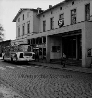 Bahnhofsgebäude: Straßenfront: Teilansicht mit Eingang: wartender Reisebus
