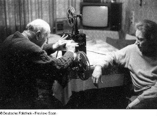 Älteres Paar mit Filmvorführgerät (Agfa Mövector ?), aufgenommen in einem Wohnzimmer in Dresden