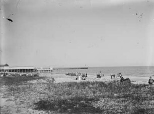 Blick auf eine Seebrücke und Urlaubern am Strand