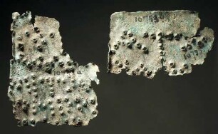 Zwei Plättchen mit weitgehend unleserlicher griechischer Inschrift (heute in drei Fragmenten vorliegend)